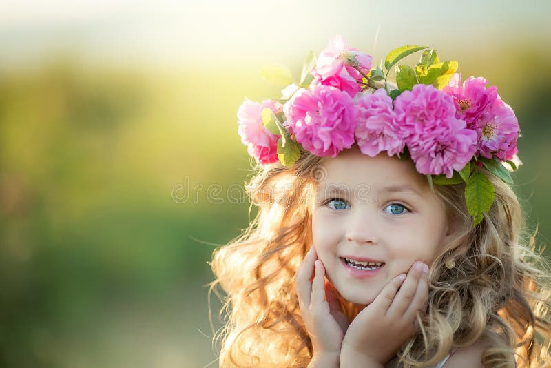 Smiling baby 3-4 year old standing with basket of flowers outdoors. Looking at camera. Summer season.