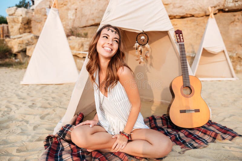 Smiling beautiful hippy girl resting at the beach tent