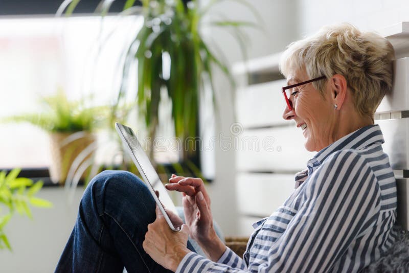Smiling beautiful senior woman using digital tablet at home royalty free stock photography