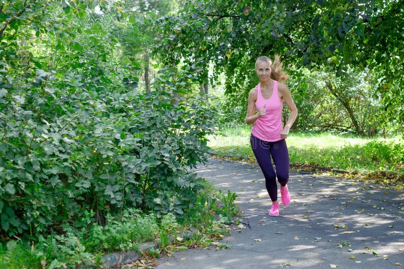 Smiling beautiful sporty woman Jogging in Park at summer royalty free stock photos Smiling beautiful sporty woman Jogging in Park at summer royalty free stock photos