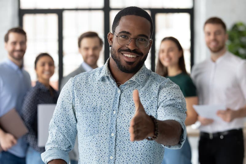 Smiling African American male employer in glasses stretch hand welcome new employee or intern in office, happy biracial boss or businessman meet greet newcomer at workplace, employment concept. Smiling African American male employer in glasses stretch hand welcome new employee or intern in office, happy biracial boss or businessman meet greet newcomer at workplace, employment concept