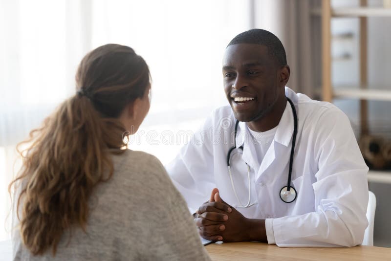 Smiling black male doctor listening female patient at medical meeting stock image Smiling black male doctor listening female patient at medical meeting stock image