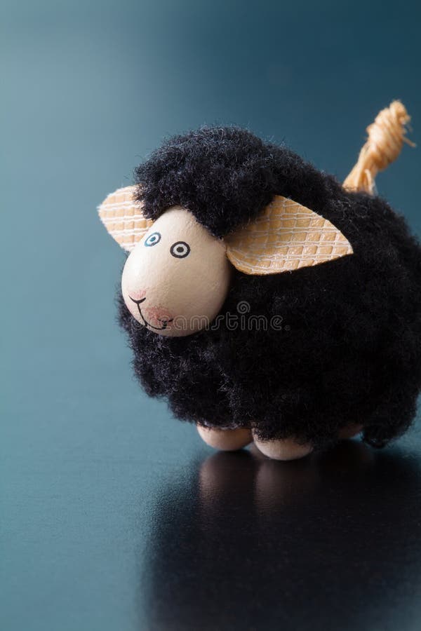 Smiling black sheep toy figurine with big ears on a blue surface