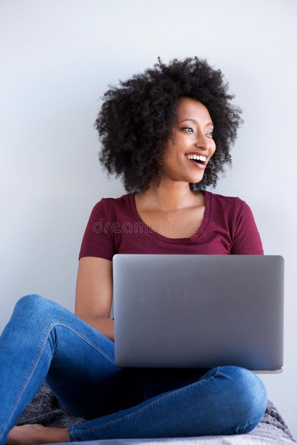 Smiling black woman relaxing at home with laptop computer