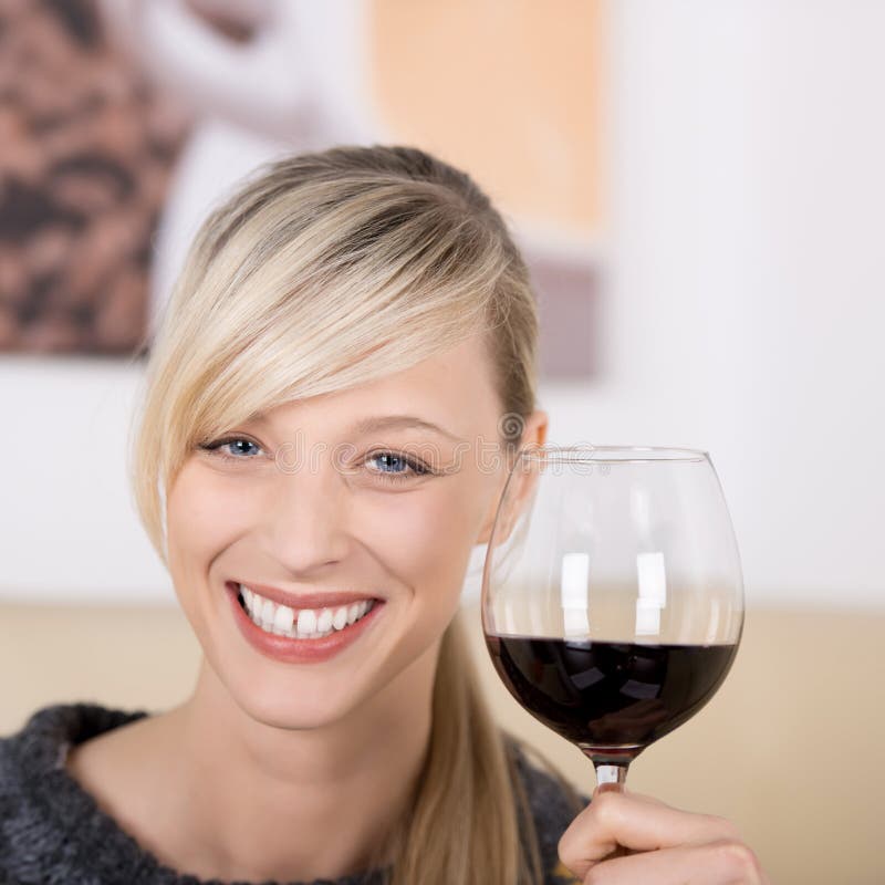 Smiling blond woman toasting with a glass of wine