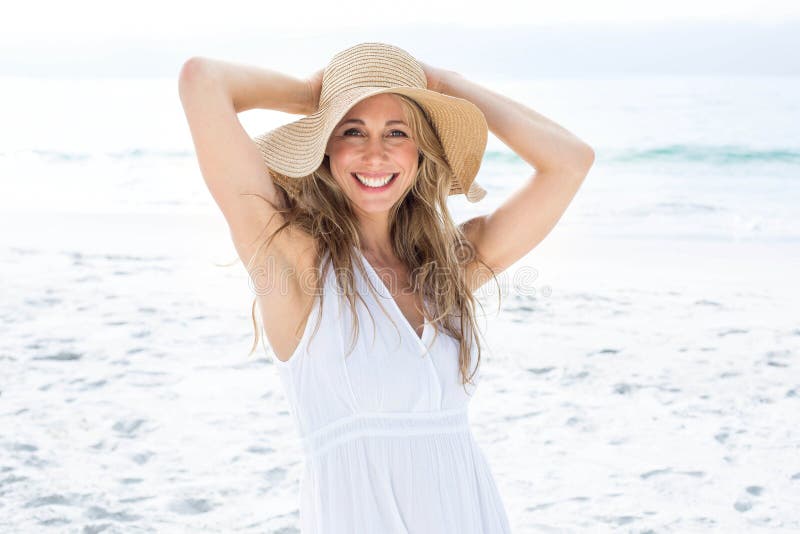 Smiling blonde in white dress looking at camera and wearing straw hat