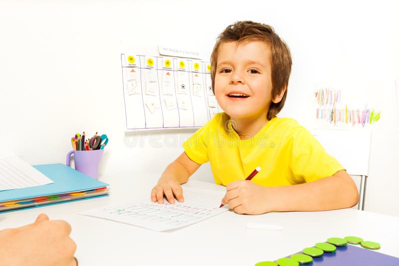 Smiling boy draws with pencil on the paper royalty free stock photos