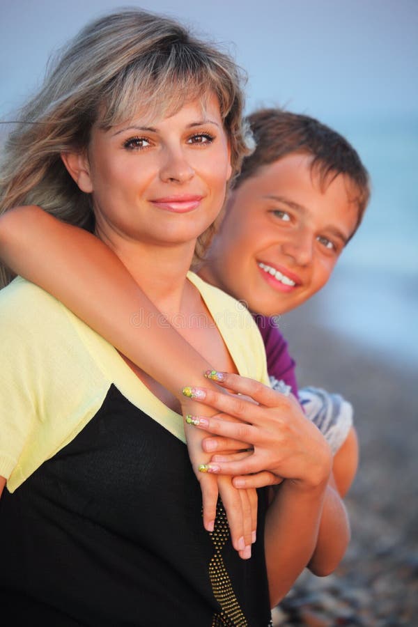 Smiling boy embraces young woman on beach