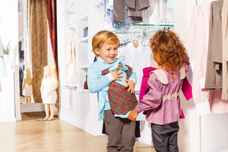 Smiling boy fitting vest and girl holding sweater