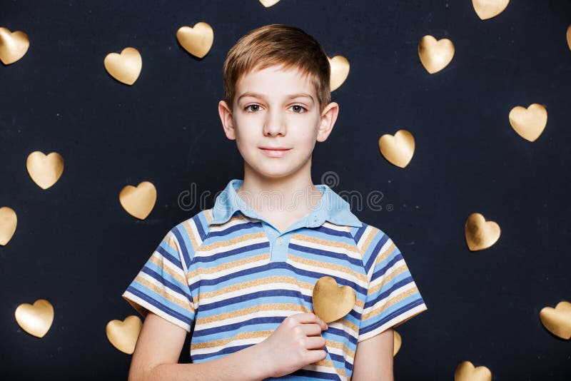 Smiling boy on golden hearts background stock photo