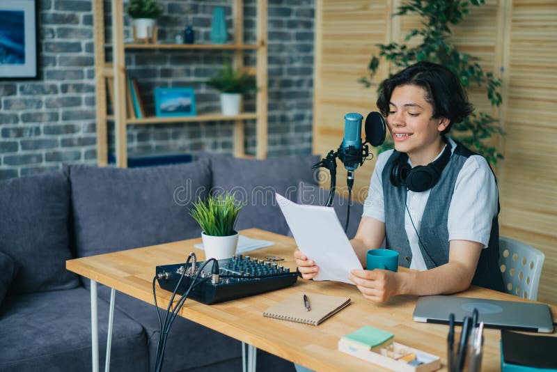 Smiling boy reading aloud in microphone recording podcast in modern studio stock photo
