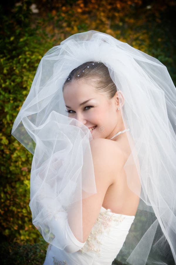 A smiling bride hides into her veil