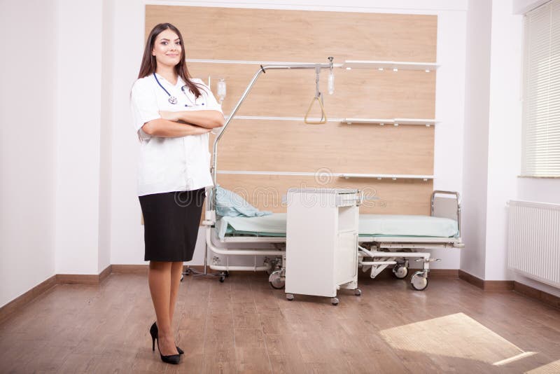 Smiling brunette woman doctor on hospital background. Physician, practitioner.