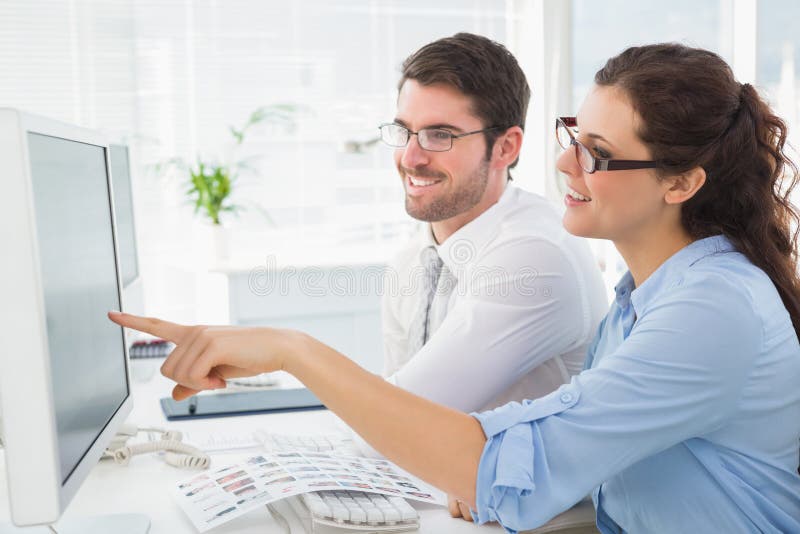 Smiling business coworkers pointing screen of computer