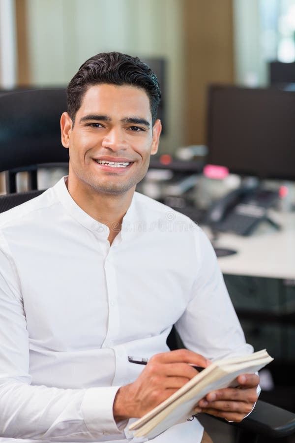 Smiling Business Executive Writing on Notebook in Office Stock Image