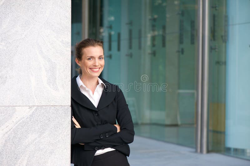 Smiling business woman standing outside office building