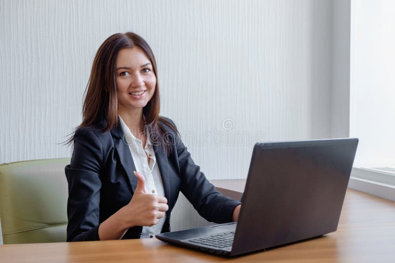 Smiling business woman working on laptop and shoving thumbs up stock images Smiling business woman working on laptop and shoving thumbs up stock images