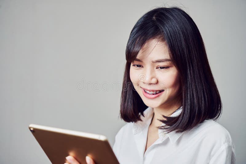 Smiling business women are holding tablet and using online applications. Gray background provides soft lighting. royalty free stock photos Smiling business women are holding tablet and using online applications. Gray background provides soft lighting. royalty free stock photos