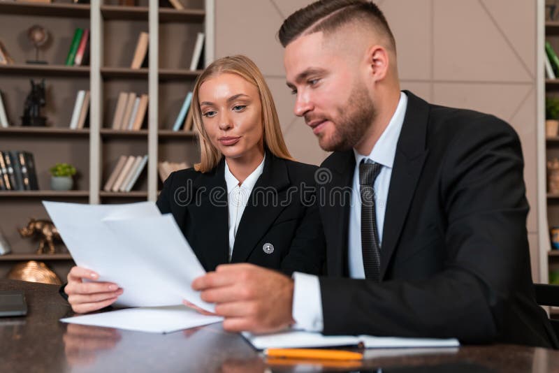 Smiling businessman and businesswoman studying business papers in office room stock images
