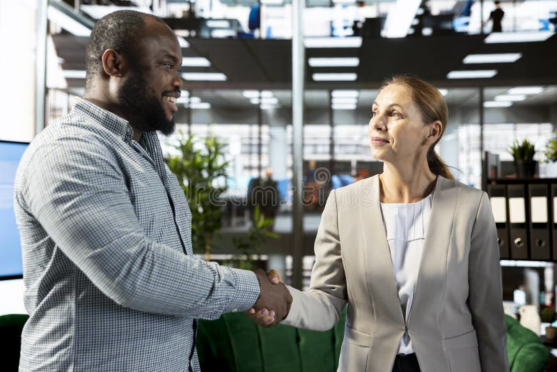 Smiling businessman doing handshake with client in office. Smiling businessman doing handshake with client in financial startup company, making deal. Upbeat men in office shaking hand of customer after agreeing terms, having discussion