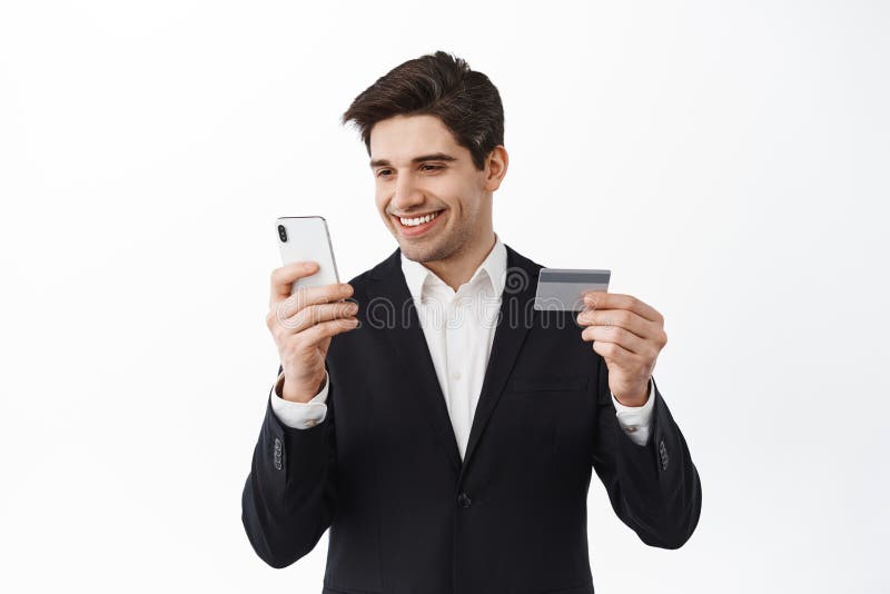 Smiling businessman paying online, show credit card and use mobile phone banking app, send money via application, shop online, standing over white background.