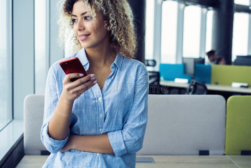 Smiling businesswoman using smartphone in office. Wearing in blue shirt royalty free stock image Smiling businesswoman using smartphone in office. Wearing in blue shirt royalty free stock image
