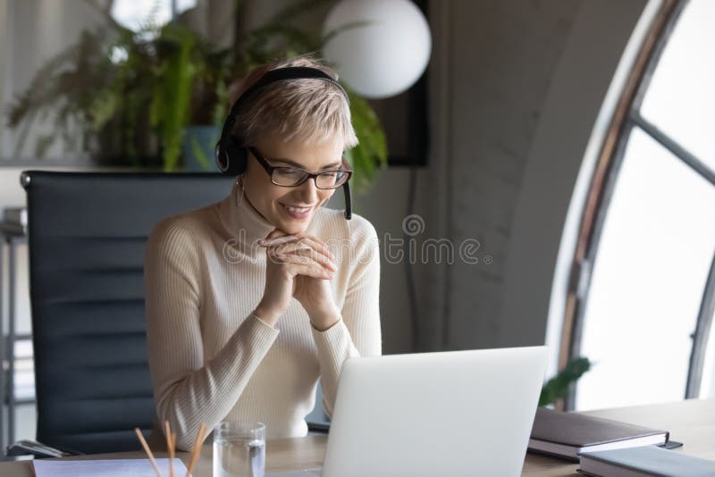 Smiling businesswoman wearing headset consulting client online in office royalty free stock photography
