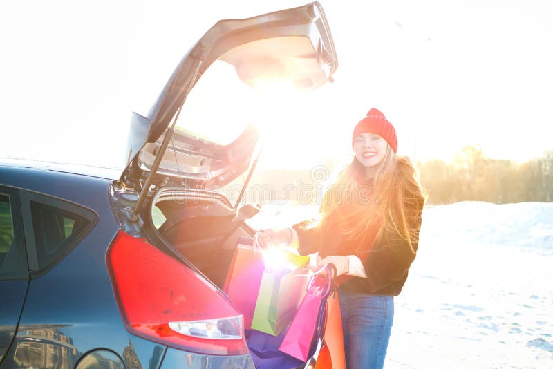 Smiling Caucasian woman putting her shopping bags into the car t