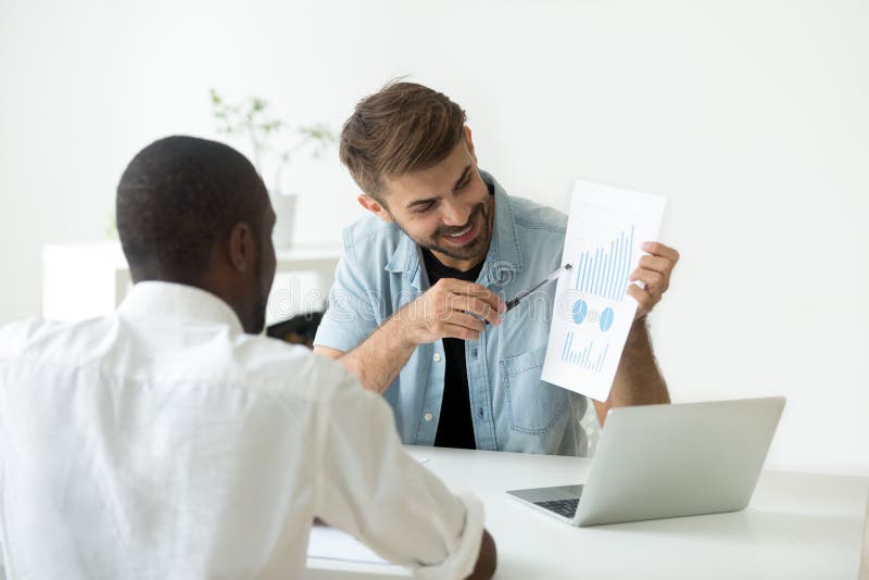 Smiling Caucasian worker explaining visual material to African A stock images
