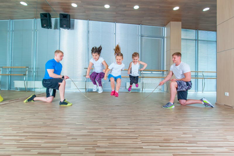 Smiling cheerful kids in school age playing together with jumping rope in gym. Children at physical education lesson in school gym