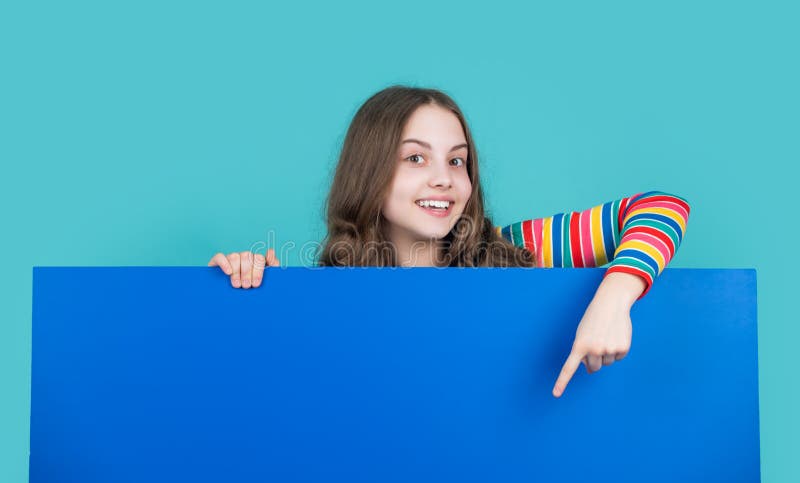 Smiling child behind blank blue paper with copy space for advertisement royalty free stock photos