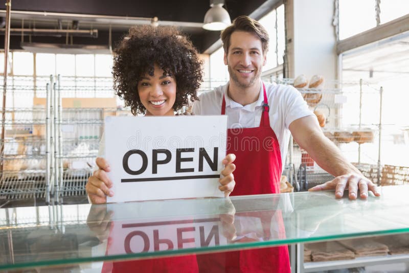 Smiling co-workers showing open sign stock photo