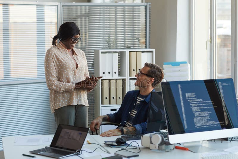 Smiling Computer Programmer Talking to Assistant stock photos