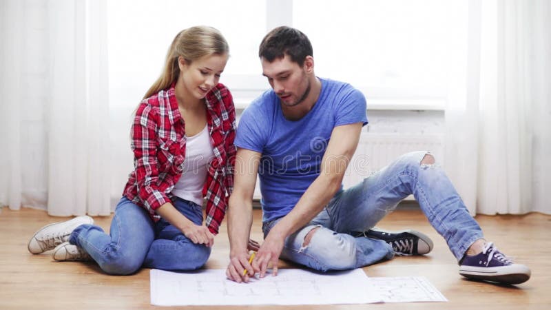 Smiling couple discussin blueprint at home
