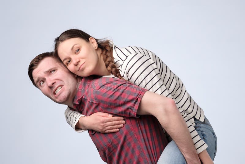 Smiling couple embracing in piggy back and looking at camera on white background royalty free stock photography Smiling couple embracing in piggy back and looking at camera on white background royalty free stock photography