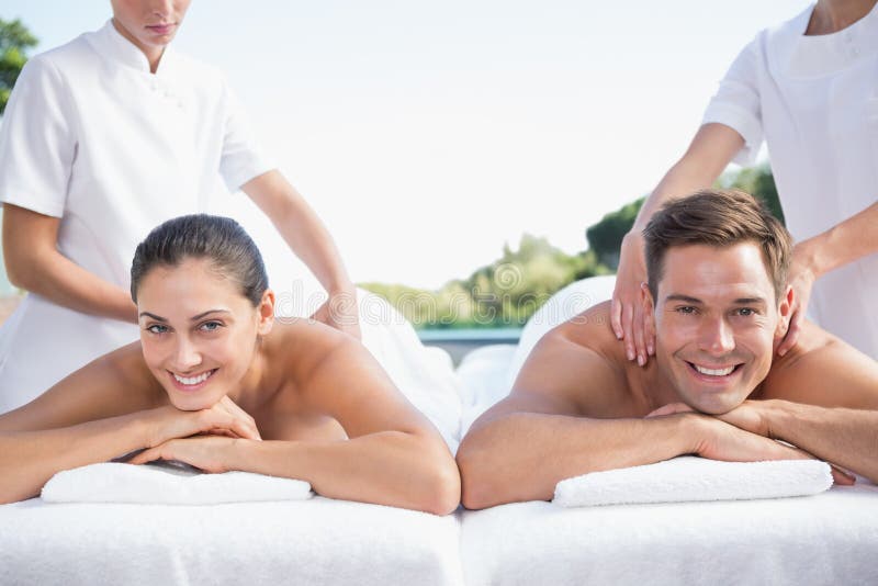 Smiling couple enjoying couples massage poolside.