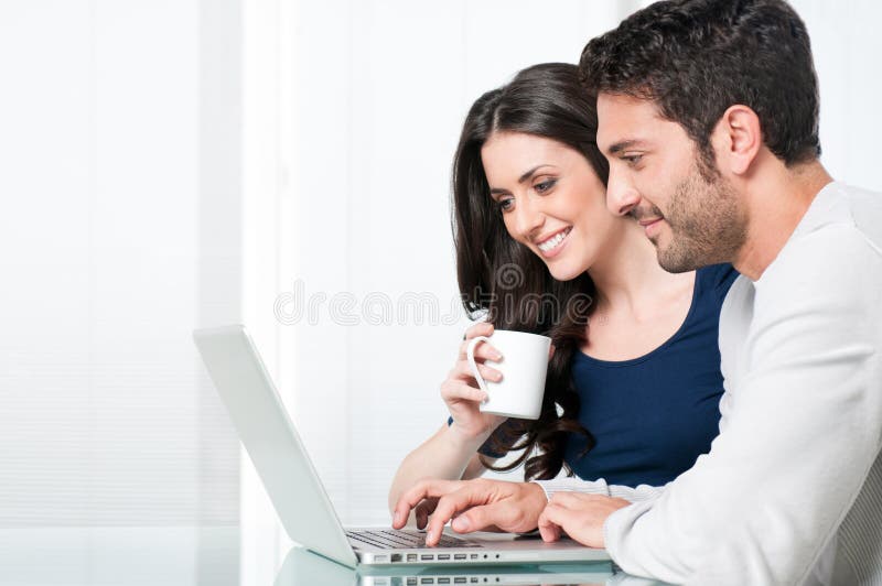 Happy modern couple surfing the net and working on laptop at home. Happy modern couple surfing the net and working on laptop at home