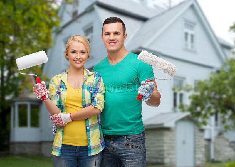 Smiling couple with paint rollers over house royalty free stock photography Smiling couple with paint rollers over house royalty free stock photography