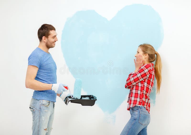 Smiling couple painting big heart on wall royalty free stock photos Smiling couple painting big heart on wall royalty free stock photos