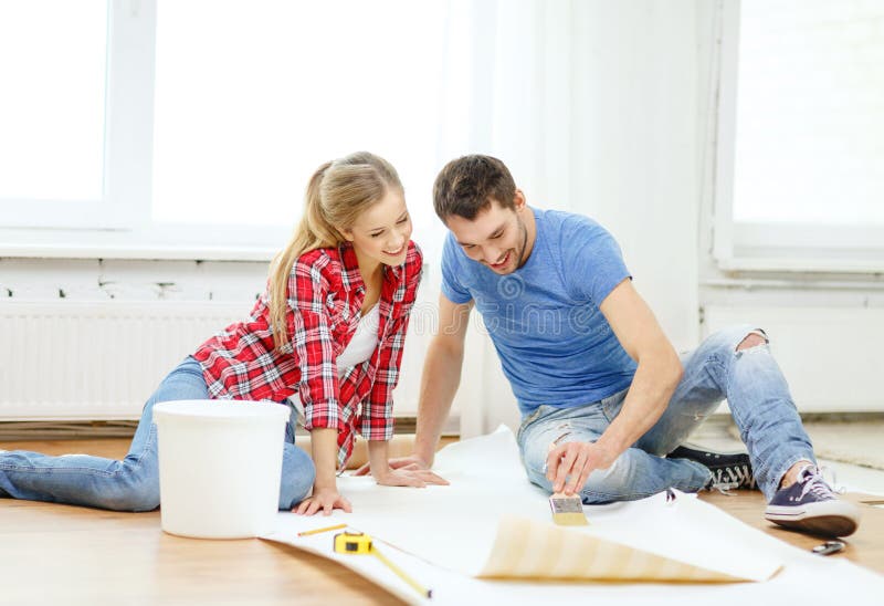 Smiling couple smearing wallpaper with glue stock photography Smiling couple smearing wallpaper with glue stock photography