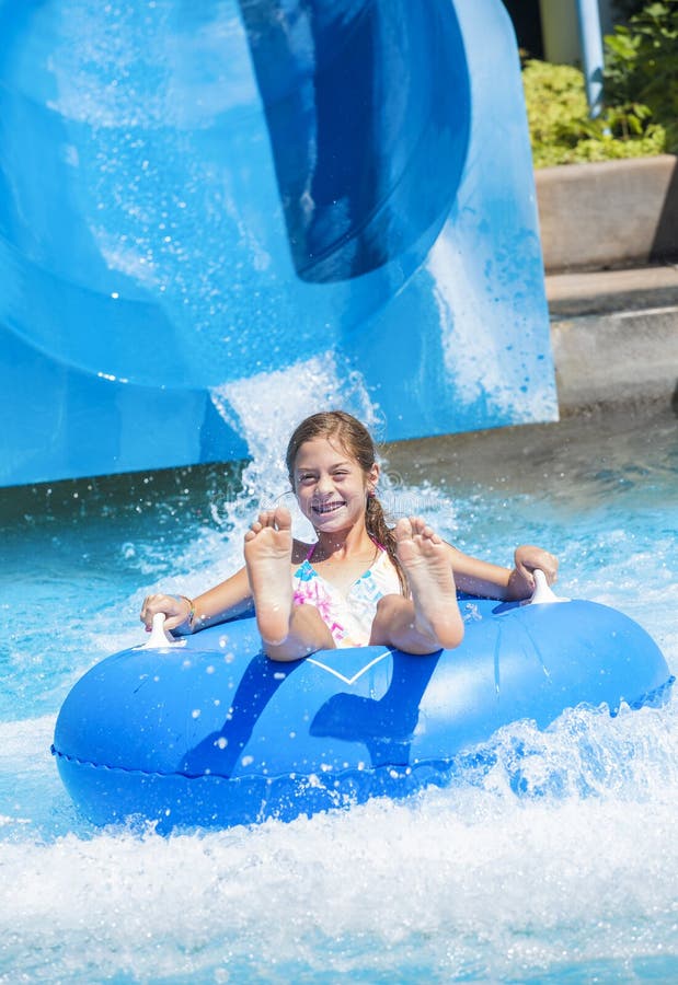 Smiling Cute little girl riding down a water slide at a water park