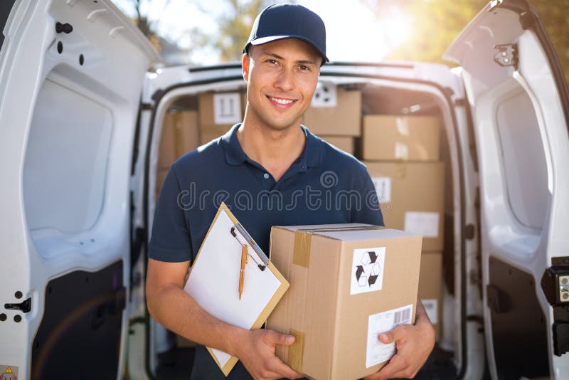 Smiling delivery man loading boxes into his truck royalty free stock images