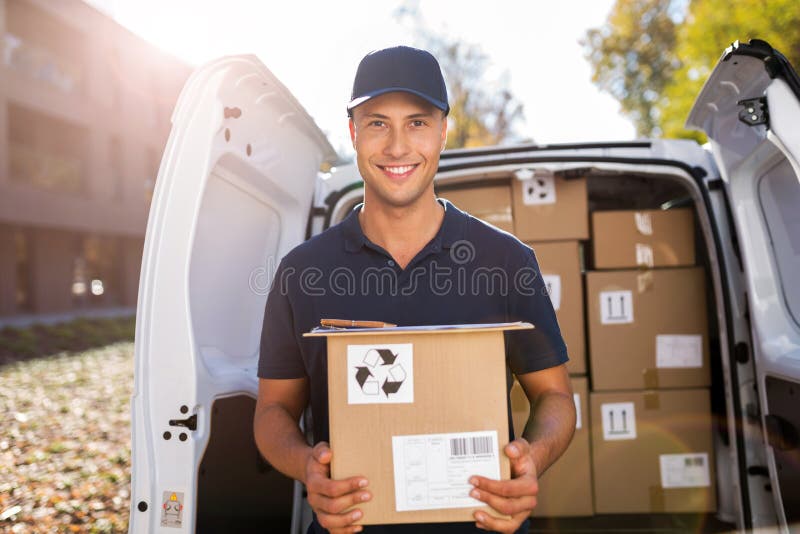 Smiling delivery man loading boxes into his truck stock image