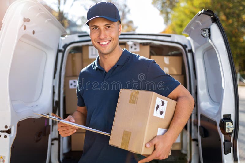 Smiling delivery man loading boxes into his truck stock photo