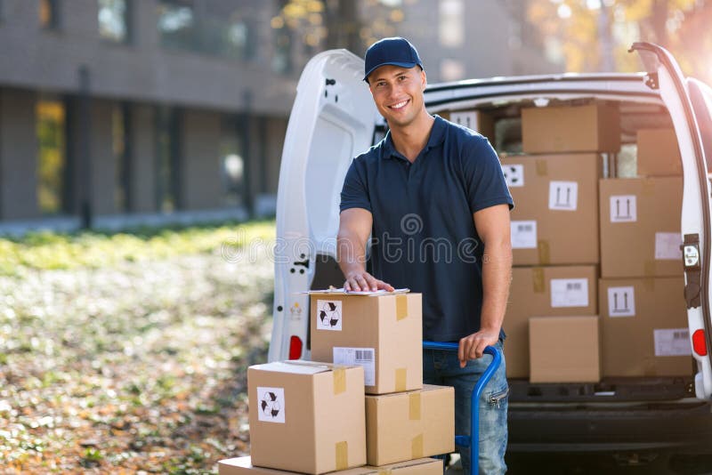 Smiling delivery man loading boxes into his truck royalty free stock image
