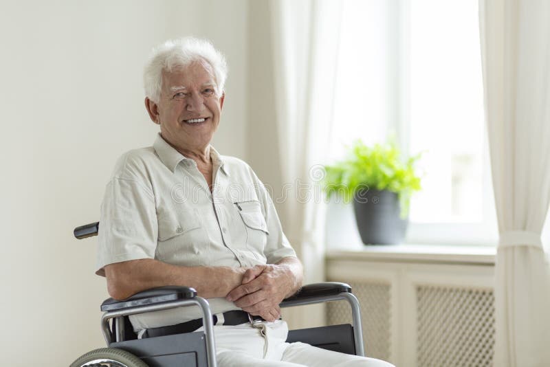 Smiling disabled senior man in a wheelchair alone at home