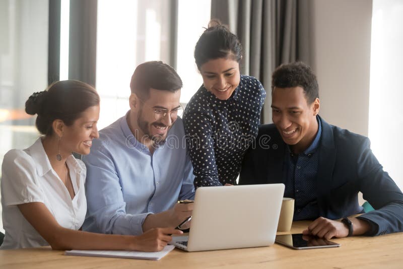 Smiling diverse employees laugh cooperating at laptop in office stock photography Smiling diverse employees laugh cooperating at laptop in office stock photography