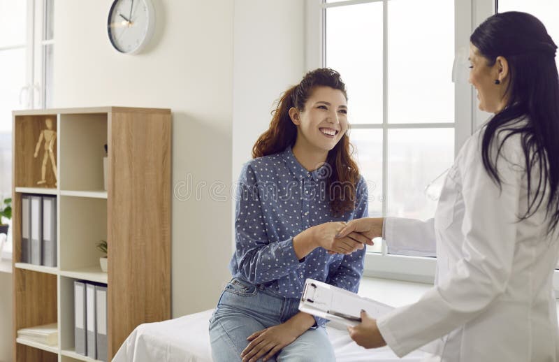 Happy young woman meeting with nurse or doctor, smiling and exchanging handshakes