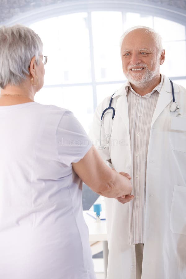Smiling doctor and patient shaking hands royalty free stock photography