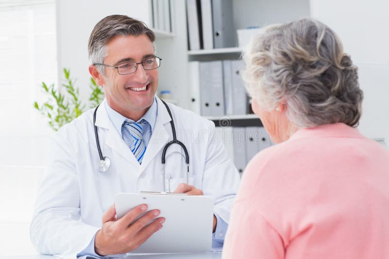 Smiling doctor writing prescriptions for patient